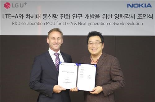 Kim Sun-tae (R), head of LG Uplus Corp.'s Service Development Division, holds the signed memorandum of understanding on technology cooperation with Andrew Cope, head of Nokia Korea, on Jan. 19, 2015. (image: LG Uplus)