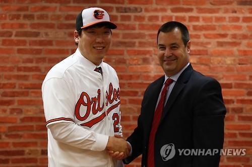 South Korean outfielder Kim Hyun-soo (L) shakes hands with Dan Duquette, executive vice president of baseball operations for the Baltimore Orioles, after signing a two-year, US$7 million deal with the club at Oriole Park in Camden Yards, Baltimore on Dec. 23, 2015. (Image : Leeco Sports Agency)