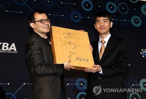 South Korean Go master Lee Se-dol (R) and Google DeepMind CEO Demis Hassabis (L) hold a wooden Go board with Lee's signature at their post-match press conference in Seoul on March 15, 2016. (Image : Yonhap)