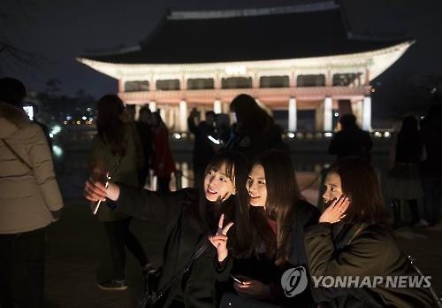 Visitors pose for selfies in front of the Gyeonghoeru Pavilion inside Gyeongbok Palace in Seoul on March 2, 2016. (Image : Yonhap)