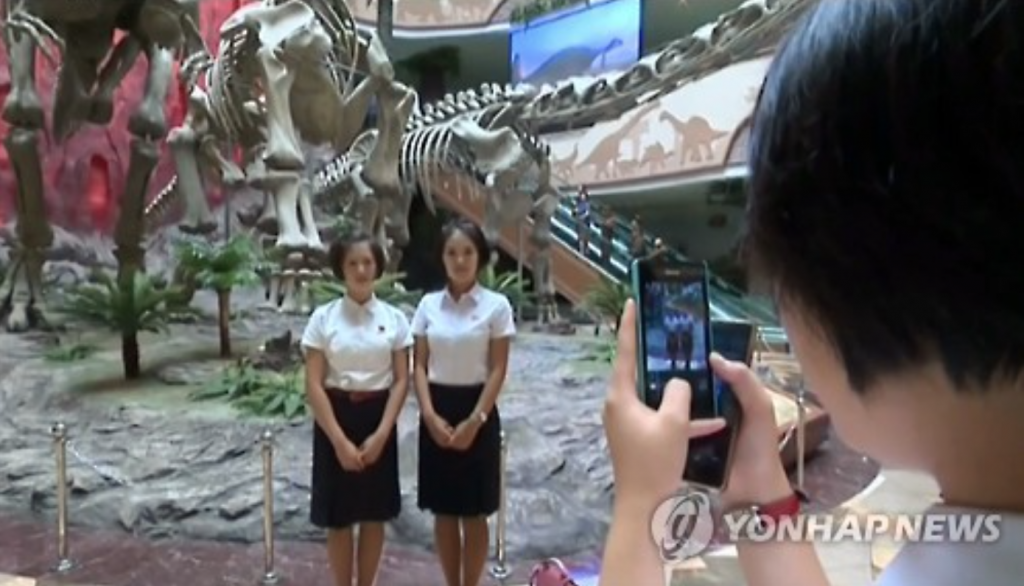 This photo, captured from the North's Korean Central TV on July 25, 2016, shows a North Korean student photographing her friends with a mobile phone at a museum in Pyongyang. (image: Yonhap)