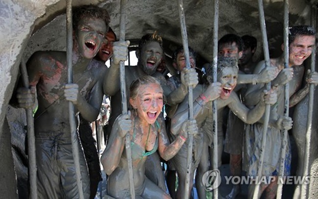 In this file photo, mud-covered tourists pretend to be trapped inside a prison at the Daecheon Beach Mud Plaza in the city of Boryeong on South Korea's west coast on July 17, 2015, as they take part in the Boryeong Mud Festival. (Image: Yonhap)