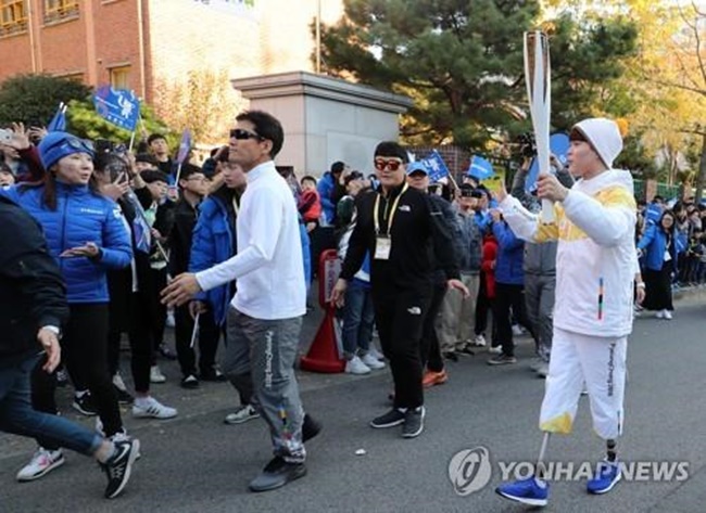 Supporters on the street cheered on the two, who ran with the Olympic flame despite their disabilities. (Image: Yonhap)
