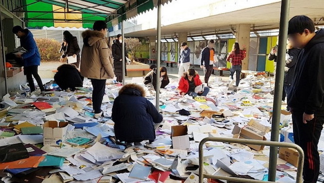 On the top floor of one hakwon in Pohang, the sight that beheld onlookers was one of chaos; young men and women rummaging through papers strewn all over the floor, conducting what appeared to be a hopeless search for what have once again become terribly valuable possessions. (Image: Yonhap)