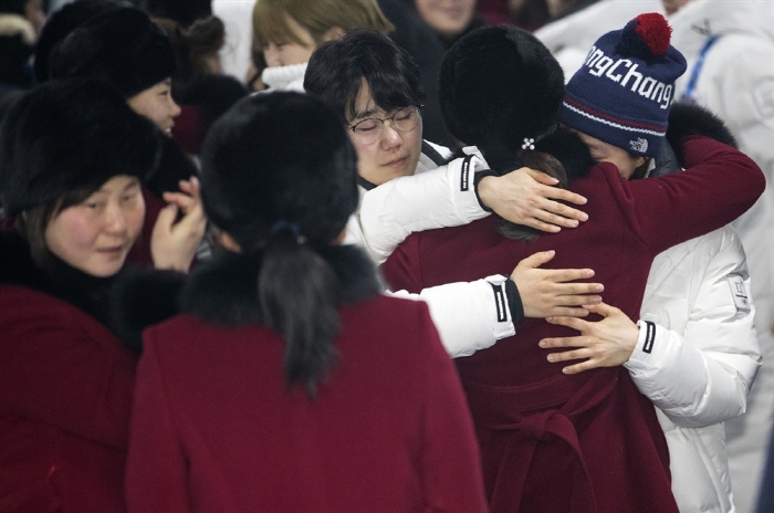 Players of the unified Korean women's hockey team exchange hugs at Gangneung Olympic Village in Gangneung, Gangwon Province, before the North Korean players (in burgundy coats) left South Korea on Feb. 26, 2018, a day after the closing ceremony of the PyeongChang Winter Olympics. (image: Yonhap)