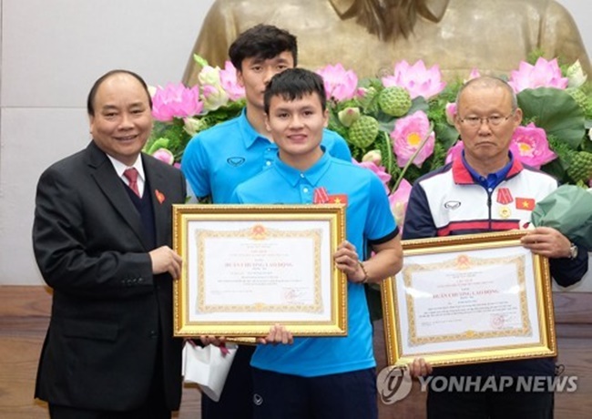 Park Hang-seo (R), the South Korean head coach of the Vietnamese U-23 football team, poses for a photo with Vietnamese Prime Minister Nguyen Xuan Phuc (L) and the team at the government building in Hanoi on Jan. 28, 2018, after receiving the third Labor Medal from the prime minister for his role in Vietnam reaching the Asian U-23 Championship final, in this photo from the Vietnamese government's website. (Image: Yonhap)