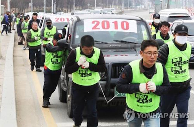 Comparing themselves to cows pulling a plow, 150 fired employees of Ssangyong Motor and civic group members in the city of Pyeongtaek pushed and pulled ten of the South Korean automaker's vehicles on the road as part of a rally calling for the reinstatement of fired workers. (Image: Yonhap)