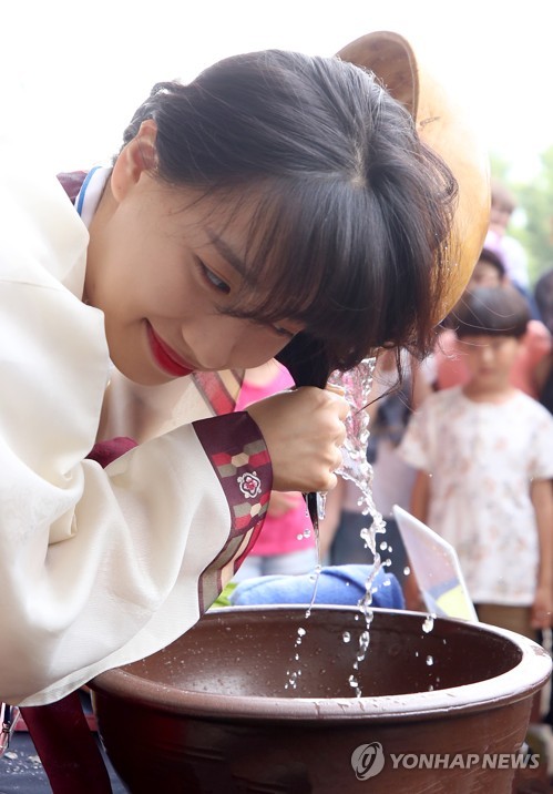 A woman washes her hair with water boiled with sweet flag during a Dano festival in Seoul on June 17, 2018, to mark Dano, a Korean traditional holiday that falls on the fifth day of the fifth month of the lunar calendar. This year's Dano falls on June 18. (Image courtesy of Yonhap)