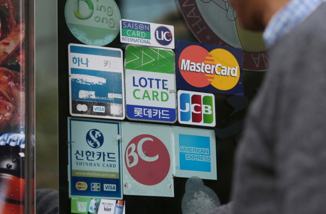 This undated file photo shows corporate logos of credit card companies in front of a store. (Yonhap)