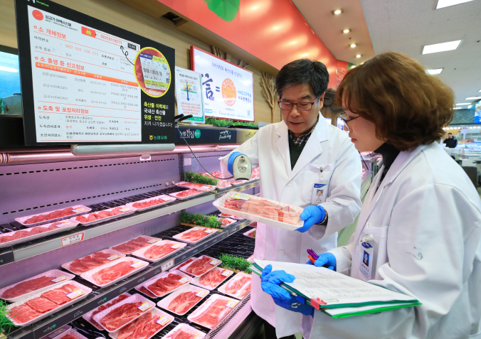Lee Su-hyun (L), the chief of the Korea Agricultural Cooperative Marketing Inc., checks beef's origin and supply chain with a cattle tracing system at a discount mart in Seoul on Jan. 31, 2018. (Yonhap)