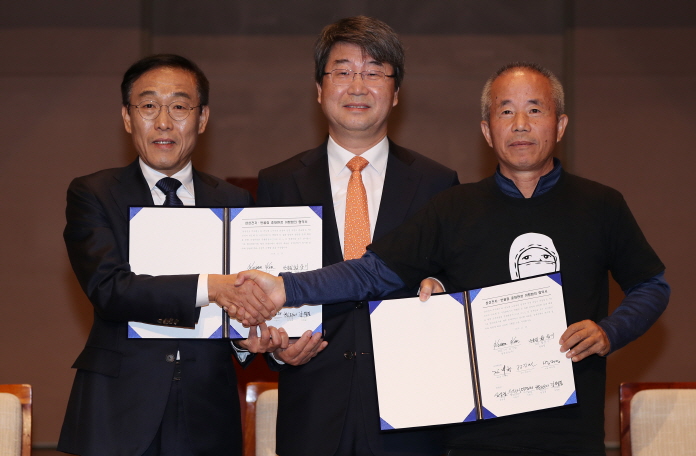 Samsung Electronics President and CEO Kim Ki-nam (L), Lawyer Kim Ji-hyung of the mediation committee (C), and Hwang Sang-ki, the head of the Supporters for the Health and Rights of People in the Semiconductor Industry, pose for a photo after signing the agreement on compensating work-related diseases in Seoul on Nov. 23, 2018. (Yonhap)
