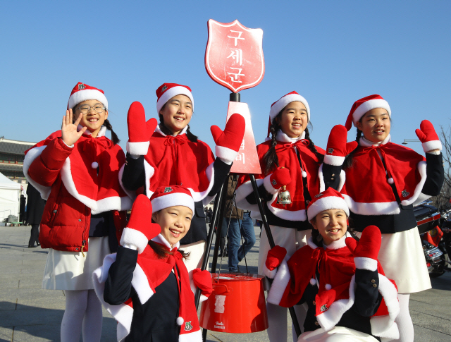 Children pose for a photo with the Salvation Army's donation kettle in central Seoul in this file photo taken Nov. 30, 2018. (Yonhap)