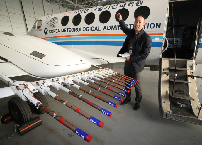 A researcher of the National Institute of Meteorological Research affiliated with the Korea Meteorological Administration explains the procedure for an artificial rain experiment in front of a KMA airplane at Gimpo International Airport in Seoul on Jan. 24, 2019. (Yonhap)