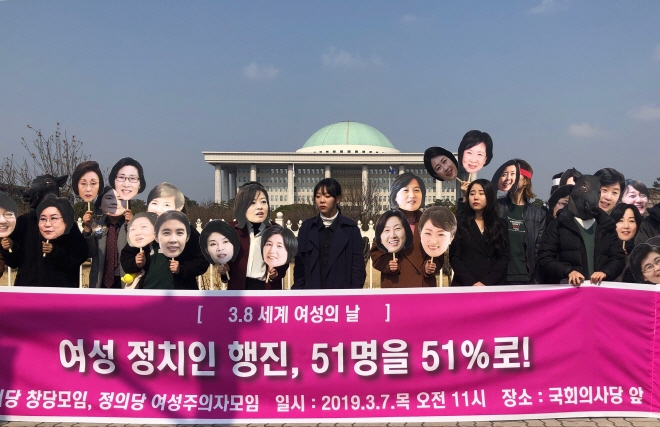 After the press conference, the activists wore masks that mimicked the faces of female members of the National Assembly and marched around the National Assembly building. (Yonhap)