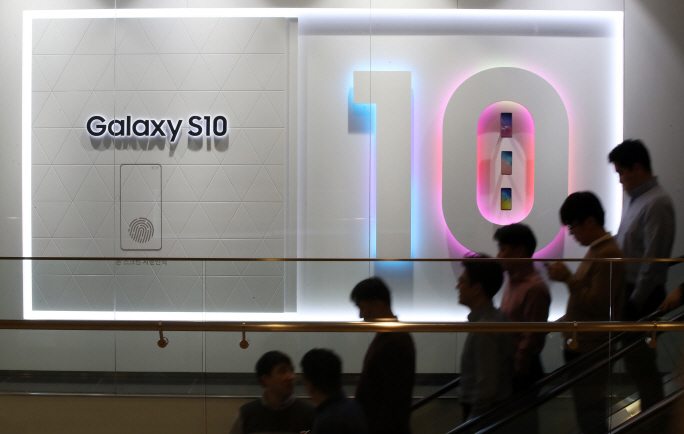 Employees of Samsung Electronics Co. walk by a signboard for the Galaxy S10 at its Seoul office on March 27, 2019. (Yonhap)