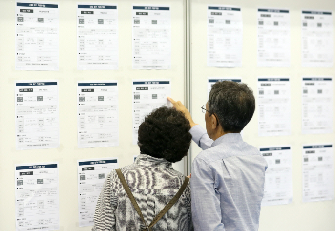 Senior job seekers looking at a bulletin board containing information on job posts at a job fair held in the southeastern port city of Busan. (Yonhap)