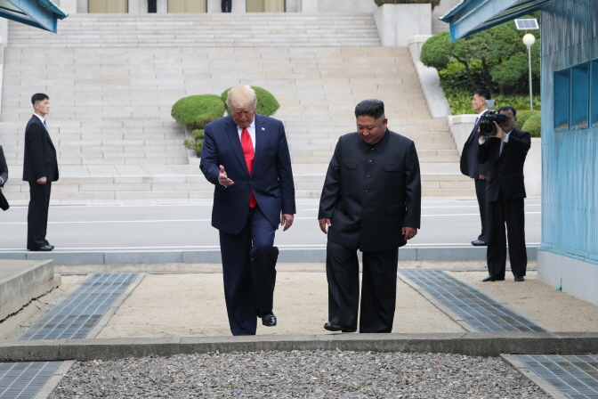 U.S. President Donald Trump (L) and North Korean leader Kim Jong-un cross the Military Demarcation Line into the southern side of the truce village of Panmunjom in the Demilitarized Zone, which separates the two Koreas, on June 30, 2019. (Yonhap)
