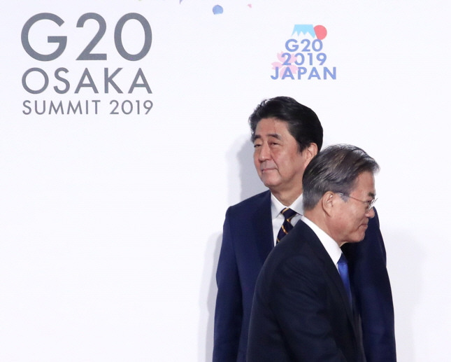 President Moon Jae-in (R) walking away after shaking hands with Prime Minister Shinzo Abe at a convention center in Osaka, the venue for a G-20 summit on June 28, 2019. (Yonhap)