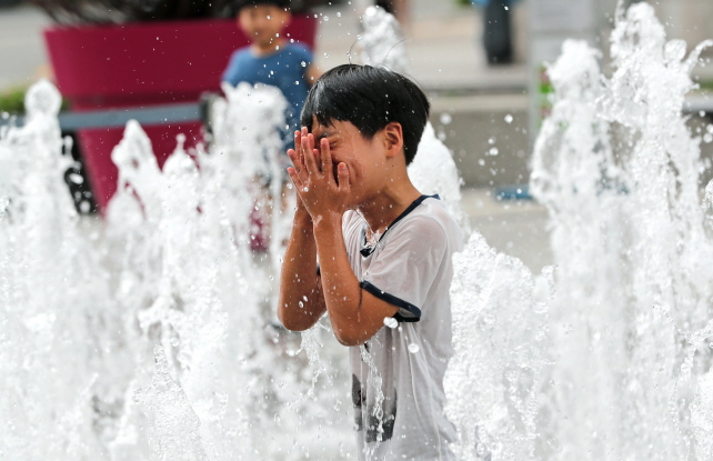 A child cools off in a public fountain in central Seoul on July 29, 2019, as a heat wave gripped much of South Korea. (Yonhap)