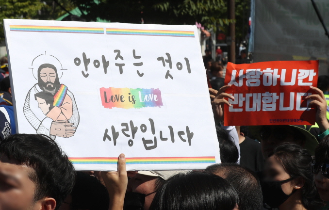LGBT participants and religious groups clash at the Incheon Queer Culture Festival on Sept. 9, 2018. A sign bearing rainbows reads "To love is to embrace" while a red opposition sign reads "We oppose because we love."(Yonhap)