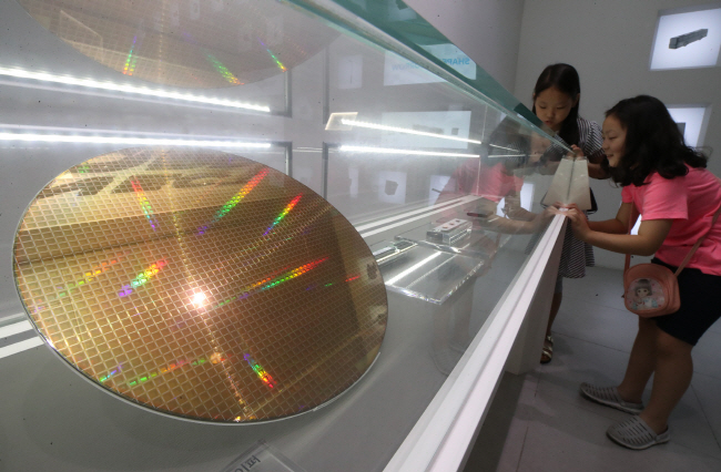 Children look at a semiconductor wafer at a promotion room of Samsung Electronics Co. in Seoul on July 31, 2019. (Yonhap)