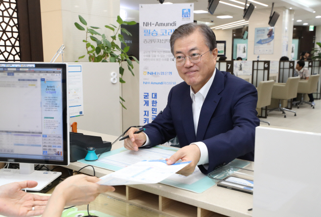 President Moon Jae-in submits a document on his plan to invest in a stock fund operated by NH-Amundi Asset Management Co. at the headquarters of NH Nonghyup Bank in Seoul on Aug. 26, 2019. (Yonhap)