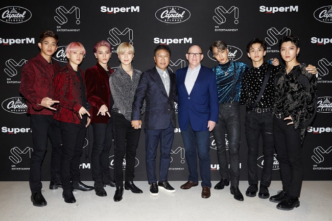 SuperM posing with Lee Su-man, CEO of SM Entertainment, and Capitol Music Group Chairman Steve Barnett. (image: SM Entertainment)