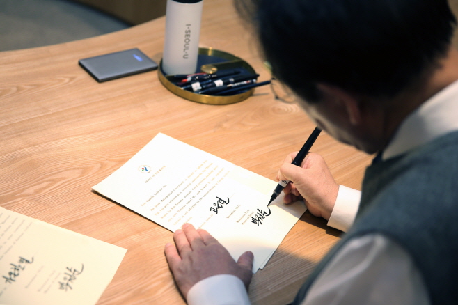 Seoul Mayor Park Won-soon signing a letter to Camille Boisvert Ko, who applied for a Korean name as part of the city's program to give foreigners Korean names. (image: Seoul Metropolitan Government)