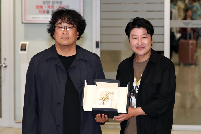 South Korean director Bong Joon-ho (L) and actor Song Kang-ho (R) show off the Palme d'Or award during a meeting with reporters at Incheon International Airport, west of Seoul, on May 27, 2019, upon returning home from Cannes, France. (Yonhap)