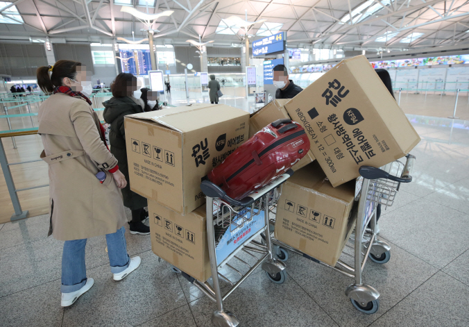 Chinese tourists push luggage carts full of boxes containing masks at check-in counters of Incheon International Airport, west of Seoul, on Feb. 3, 2020, before returning to China amid the escalating coronavirus crisis. (Yonhap)