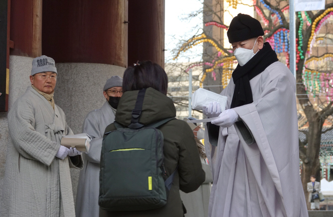 This Feb. 4, 2020, photo shows Ven. Jihyun at Jogyesa temple in central Seoul handing out a mask to a visitor. (Yonhap)
