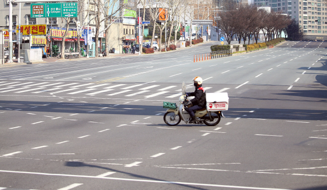 A motorcycle drives through an empty road in Daegu on Feb. 20, 2020. (Yonhap)