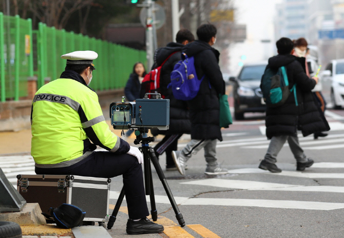 This file photo shows a police officer checking speeding vehicles in a school zone. (Yonhap)