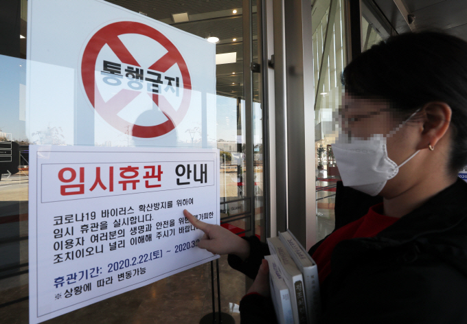 A visitor reads a notice of closure on a gate of the National Library of Korea, Sejong, on Feb. 23, 2020. (Yonhap)