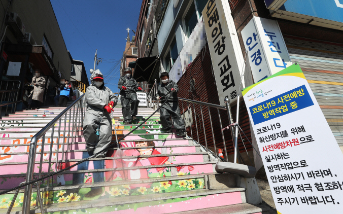 Seongnam city officials disinfect the neighborhood of River of Grace Community Church, where 46 members have tested positive for the coronavirus, on March 16, 2020. (Yonhap)
