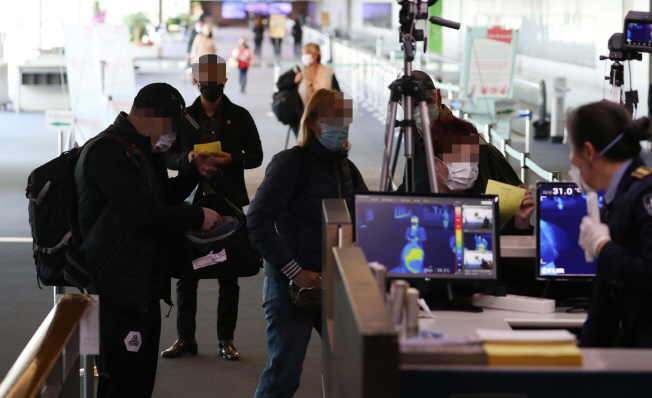 Passengers arriving at Incheon International Airport, west of Seoul, are individually checked for fever by quarantine officials on March 19, 2020. (Yonhap)