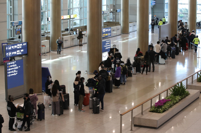 Passengers from London are in line in the arrival lobby of Incheon International Airport, west of Seoul, on March 23, 2020, to be bused to a nearby hotel, where they will undergo COVID-19 tests. (Yonhap)
