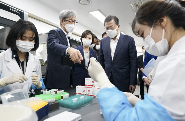South Korean President Moon Jae-in (C) watches researchers at Seegene Inc. test COVID-19 diagnostic reagents at the company's research facility in Seoul on March 25, 2020. (Yonhap)