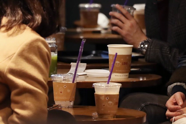 Customers have coffee in disposable cups at a Seoul coffee shop on Feb. 25, 2020, as the Seoul city government temporarily allowed disposable products at cafes and restaurants amid the spread of the new coronavirus in the country. (Yonhap)