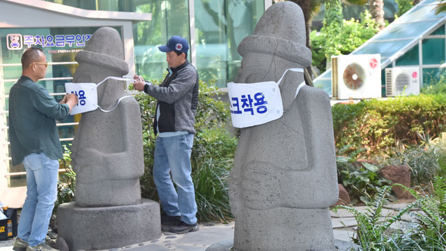 Officials in Jeju put masks on "dolhareubang" statues, a basalt totem statue that is a symbol of the tourist island, on April 28, 2020. (Yonhap)