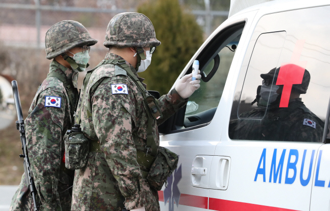 In this file photo, taken on Feb. 26, 2020, troops belonging to the Army's 50th division check the driver of an ambulance for fever near its base in northern Daegu, 300 kilometers southeast of Seoul. (Yonhap)