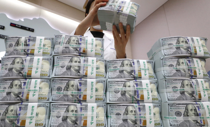 In the photo, taken March 31, 2020, a Bank of Korea (BOK) official is seen inspecting U.S. banknotes, set to be delivered to local banks as the first batch of U.S. dollar injections under the BOK's bilateral currency swap arrangement with the U.S. Fed. (Yonhap)