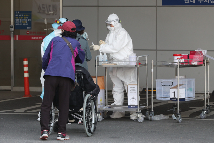 This photo taken on April 2, 2020, shows a health worker checking visitors at St. Mary's Hospital in Uijeongbu, north of Seoul, where group infection of the new coronavirus has been reported. (Yonhap)