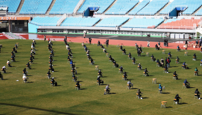 This photo, taken on April 4, 2020, shows people taking a company entrance test at an outdoor stadium in Ansan, outside of Seoul. Applicants were seated five meters apart from each other. (Yonhap)