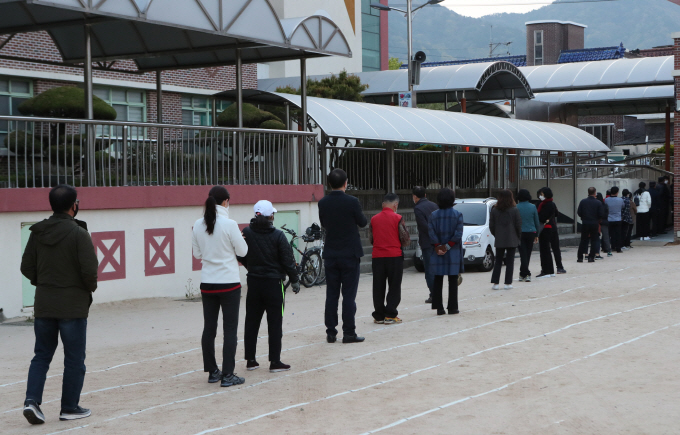 Voters form a long line to cast their ballots at a polling station in the southeastern city of Changwon on April 15, 2020, as South Koreans began voting the same day to elect a new parliament amid the outbreak of the new coronavirus. (Yonhap)