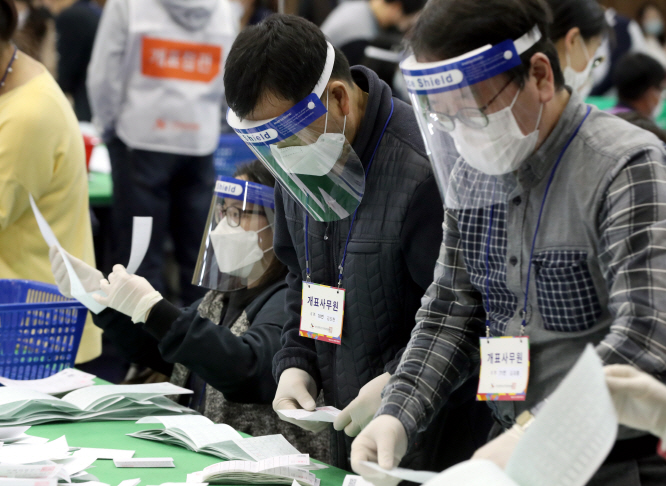 Officials wearing protective face guards, masks and plastic gloves go through ballots at a middle school stadium in the southern port city of Busan on April 15, 2020. (Yonhap)
