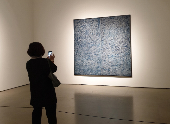 A visitor takes a photo of Kim Whan-ki's "Universe" at Gallery Hyundai in Seoul on May 12, 2020. (Yonhap)