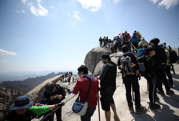 The Baekwundae peak on Mount Bukhan in Seoul is crowded with hikers on April 26, 2020, the first Sunday since the government eased its social distancing rules amid a slowdown in new coronavirus cases. (Yonhap)