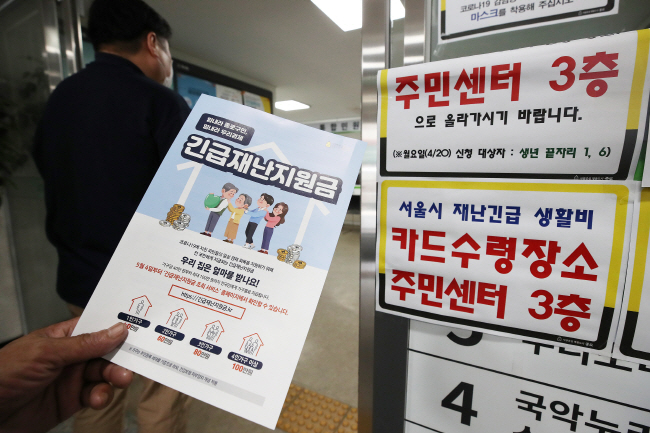 A citizen looks at materials explaining how to receive emergency disaster relief funds at a community center in Seoul on May 4, 2020. (Yonhap)