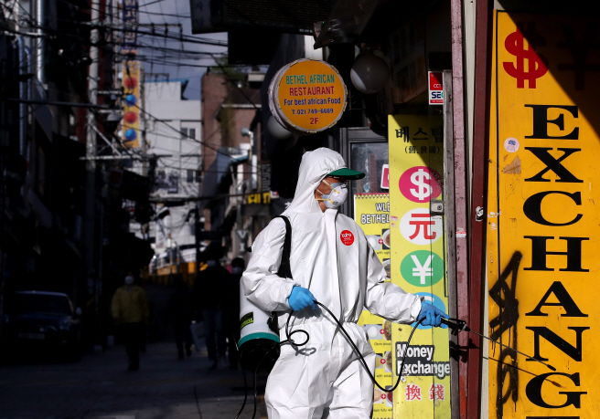 Volunteer workers disinfect a storefront at a street in the central Seoul neighborhood of Itaewon on May 12, 2020. (Yonhap)